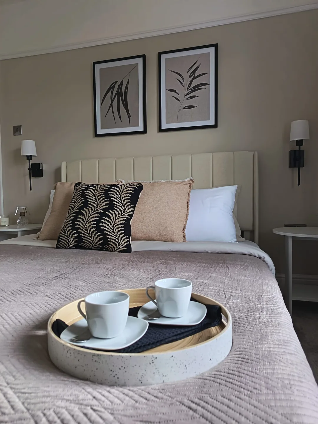 Beautifully staged neutral bedroom with botanical artwork and a breakfast tray